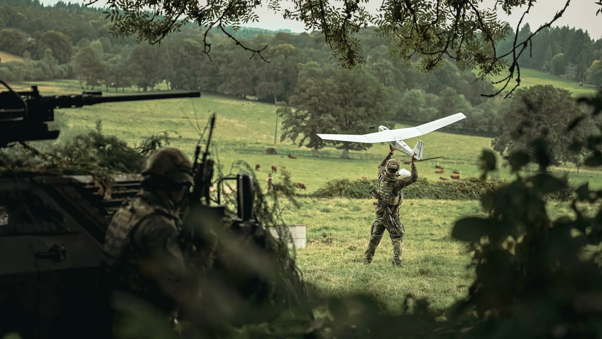 Een militair werpt een drone vooruit in een grasveld.