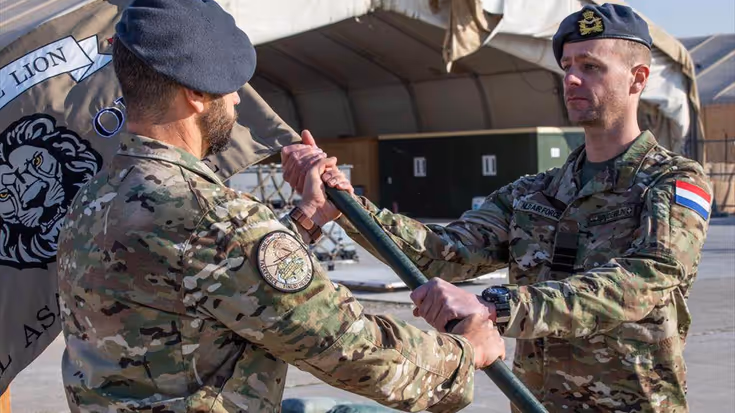 Militair overhandigt vlag aan andere militair.