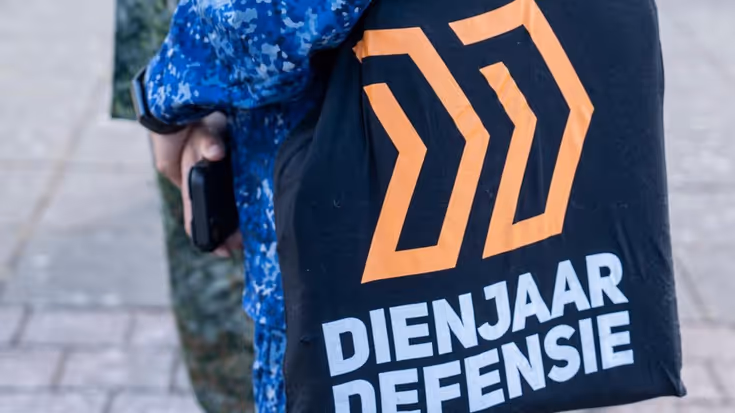 Een militair draagt een tas van Dienjaar Defensie.