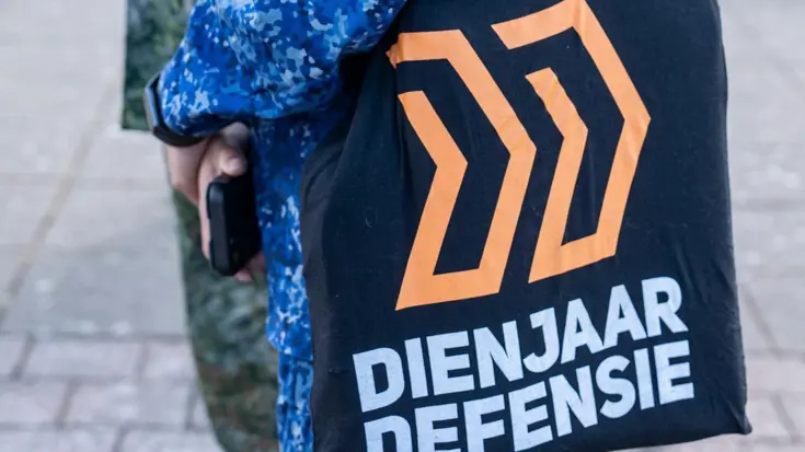 Een militair draagt een tas van Dienjaar Defensie.