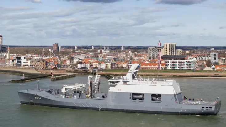 Zr.Ms. Den Helder met op de achtergrond een stad.