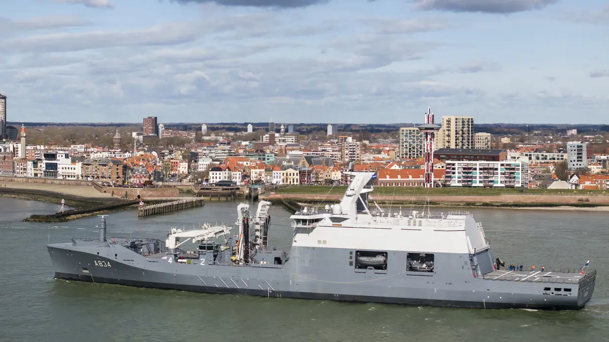 Zr.Ms. Den Helder met op de achtergrond een stad.