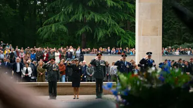  Militairen staan in de houding   Mensen lopen langs het monument 