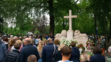 Publiek voor het Nationaal Monument op de Grebbeberg, waarvoor kransen staan en liggen. 