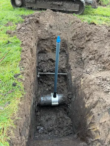 een blauwe staaf die met een klem op de leiding is gemonteerd.