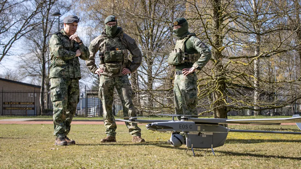 De CDS kijkt met andere militairen naar een drone. 