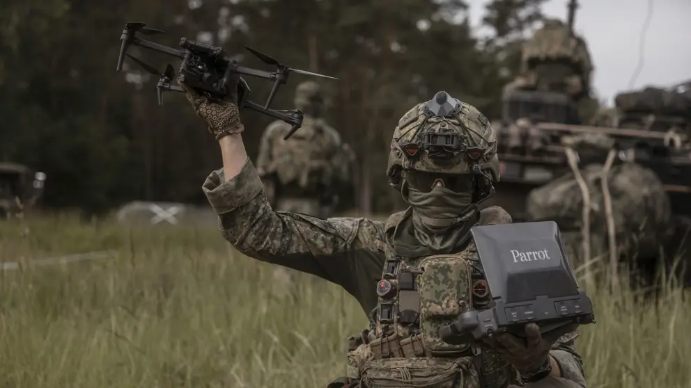 Een militair houdt een drone in de lucht. 