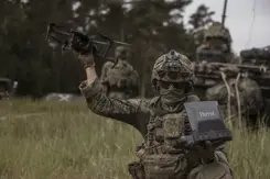 Een militair houdt een drone in de lucht. 