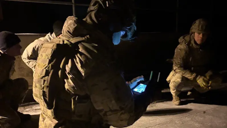 Militair kijkt in het donker naar schermpje om drone te bedienen. 