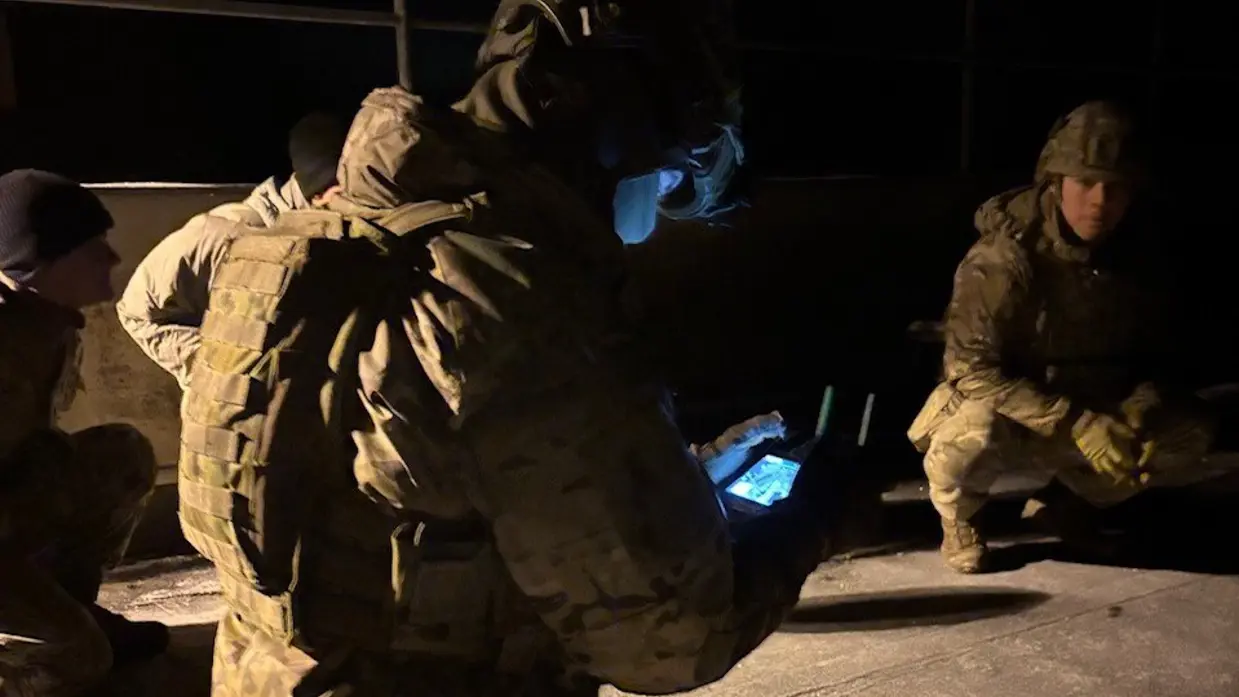 Militair kijkt in het donker naar schermpje om drone te bedienen. 