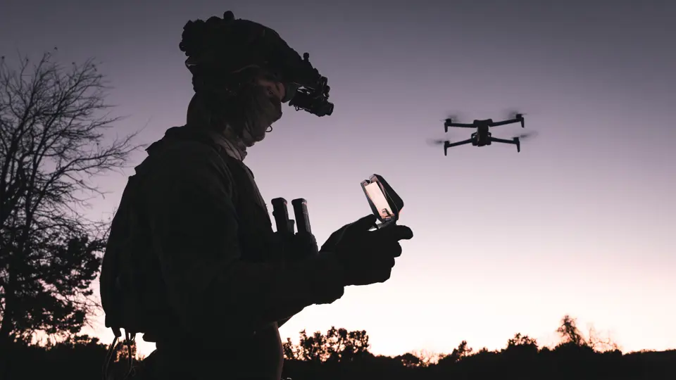 Militair bestuurt drone bij zonsondergang.