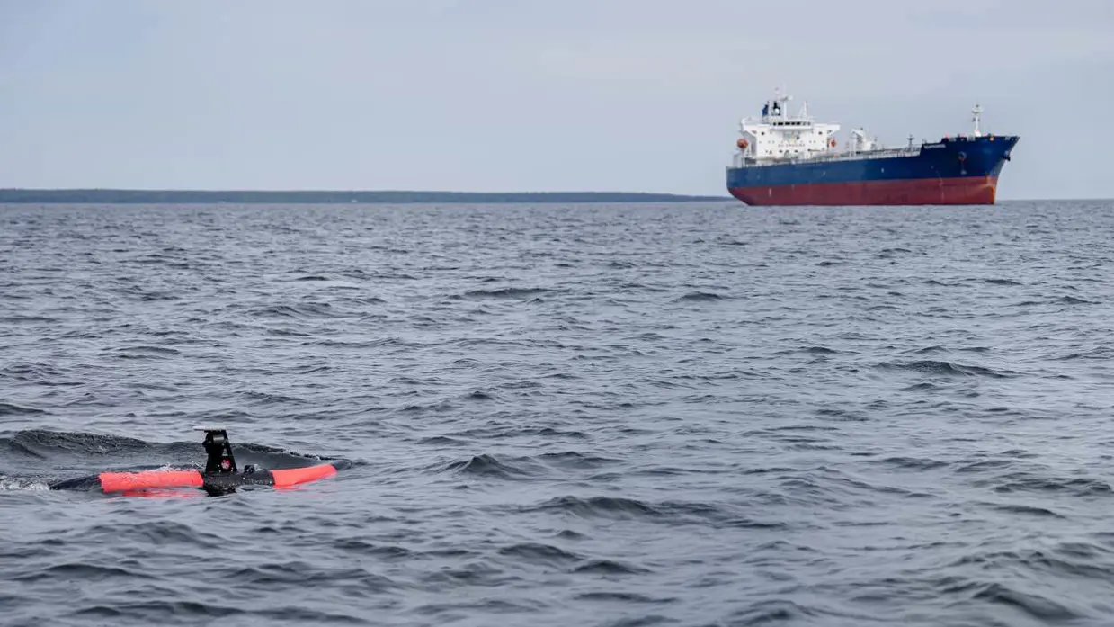 De Scout in zee met een schip op de achtergrond.