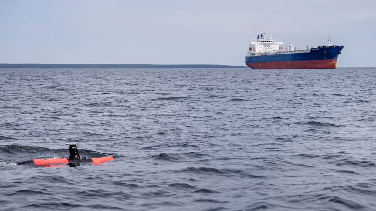 De Scout in zee met een schip op de achtergrond.