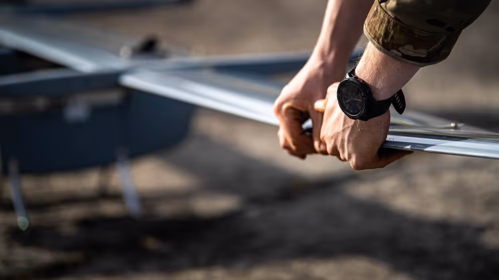 Militair houdt vleugel van drone vast.