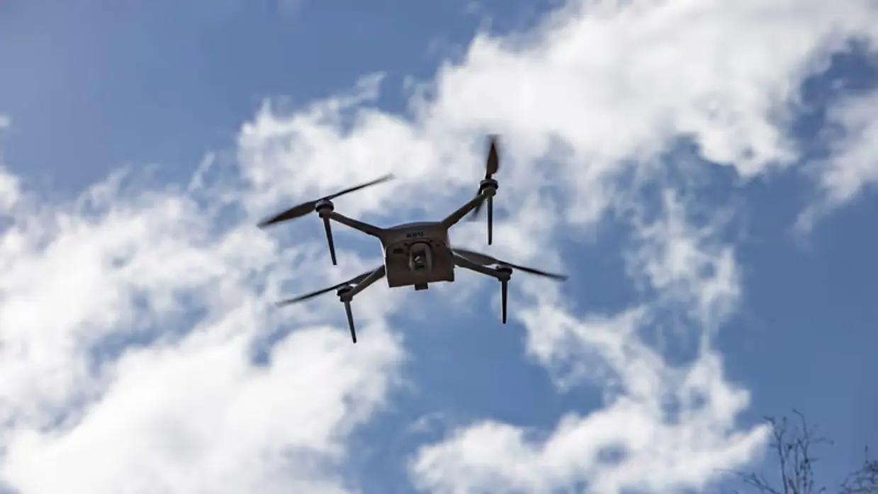 Een drone vliegt door de strak blauwe lucht.  