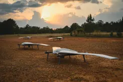 Vier drones staan op open veld in bosrijke omgeving.