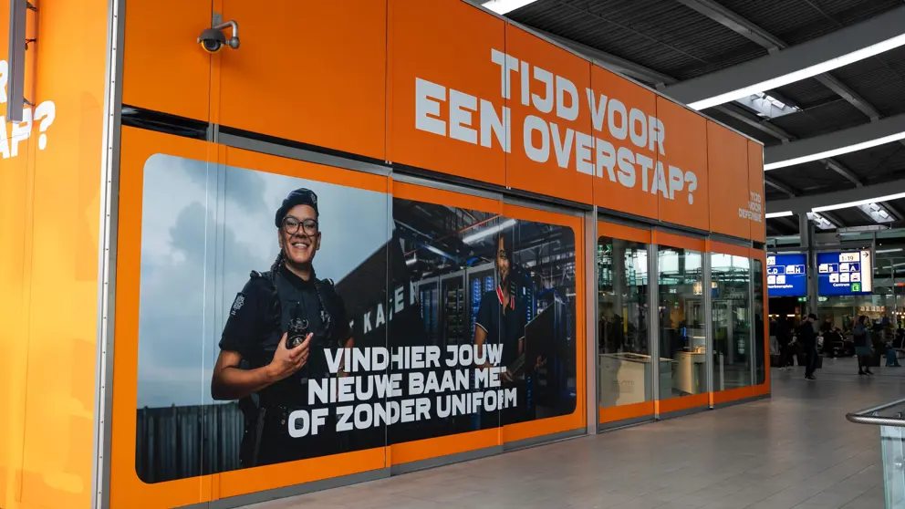 Oranje pop-up store met een foto van een vrouwelijke militair en de tekst: Tijd voor een overstap? 