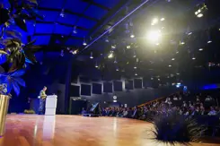 Een man voor een spreekgestoelte voor een gevulde zaal