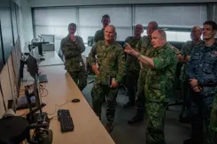 Militairen staan in een ruimte naar schermen te kijken.