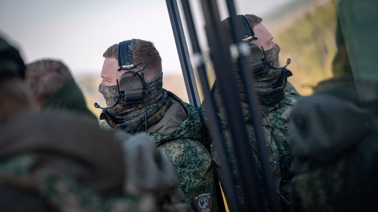 Twee militairen staan klaar, aan de rechterkant is hun reflectie in een oppervlakte te zien.