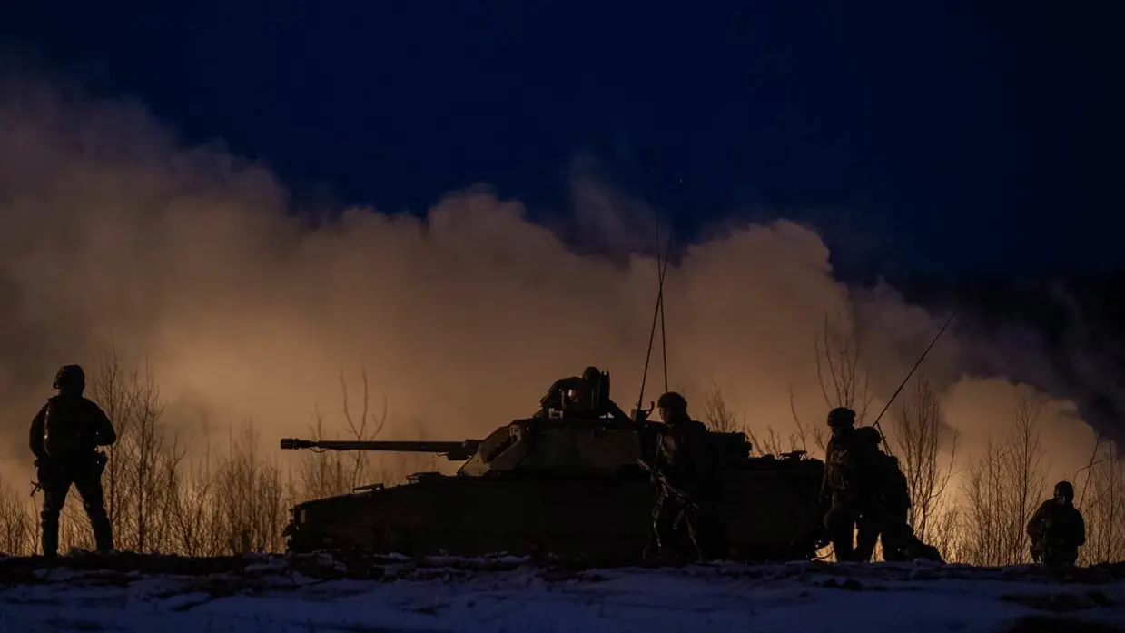 Tank en militairen in het donker.