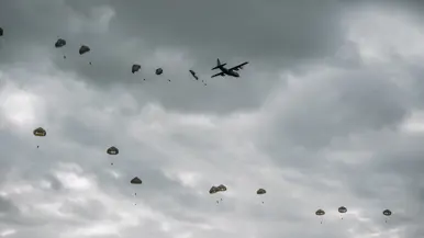 Tientallen parachutisten hangen in de lucht nadat ze uit een vliegtuig zijn gesprongen.