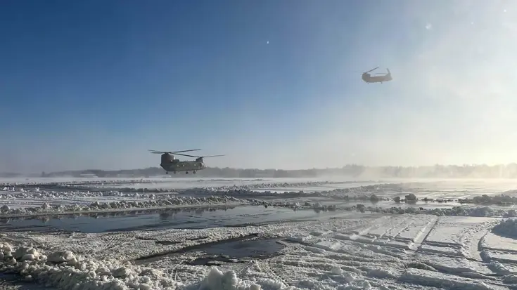 Helikopters stijgen op boven een sneeuwlandschap.