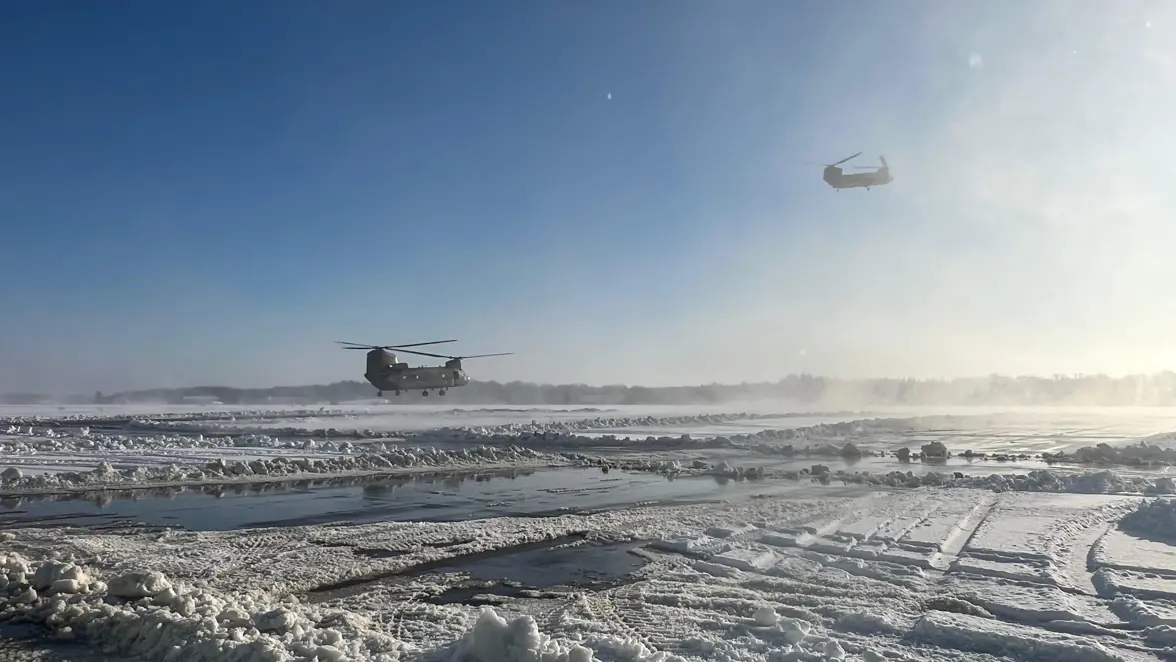 Twee Chinooks boven een besneeuwd platform.