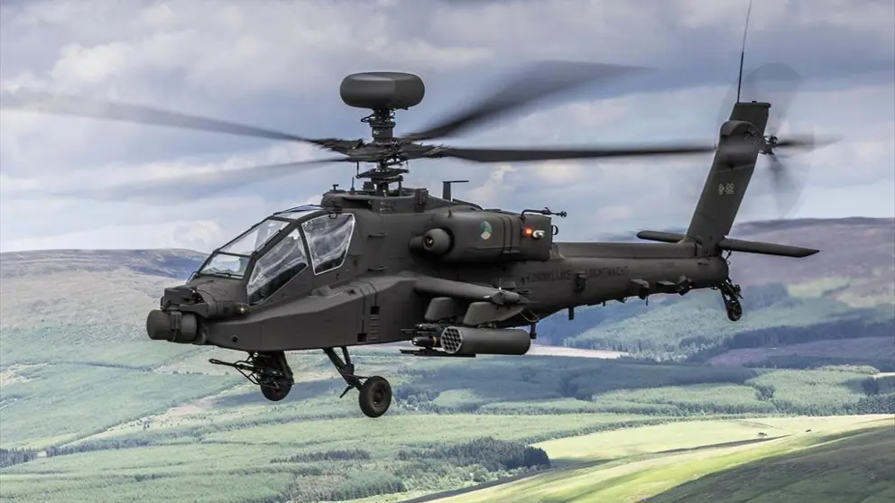Een lviegende Apache gevechtshelikopter met heuvels op de achtergrond.