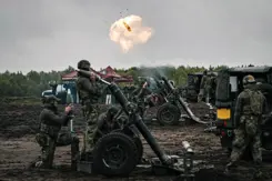 Een rookwolk in de lucht en enkele 120mm mortieren en militairen er omheen.