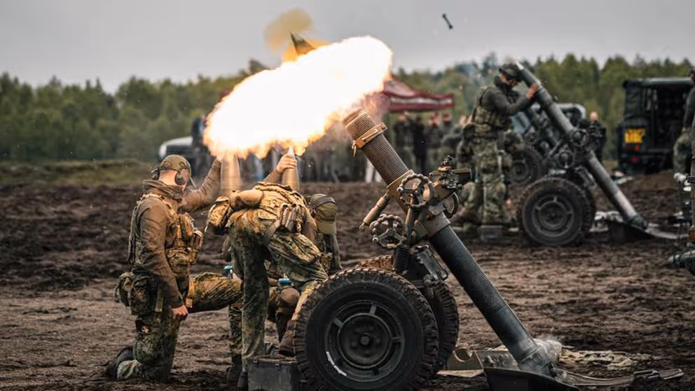Vuurbal bij afschieten mortier. Militairen staan erbij.