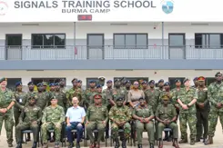 Groepsfoto van Nederlandse trainers en lokale militairen voor een trainingslocatie. 