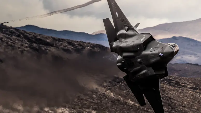Een F-35 scheert door de lucht, op de achtergrond zijn bruine bergen te zien 