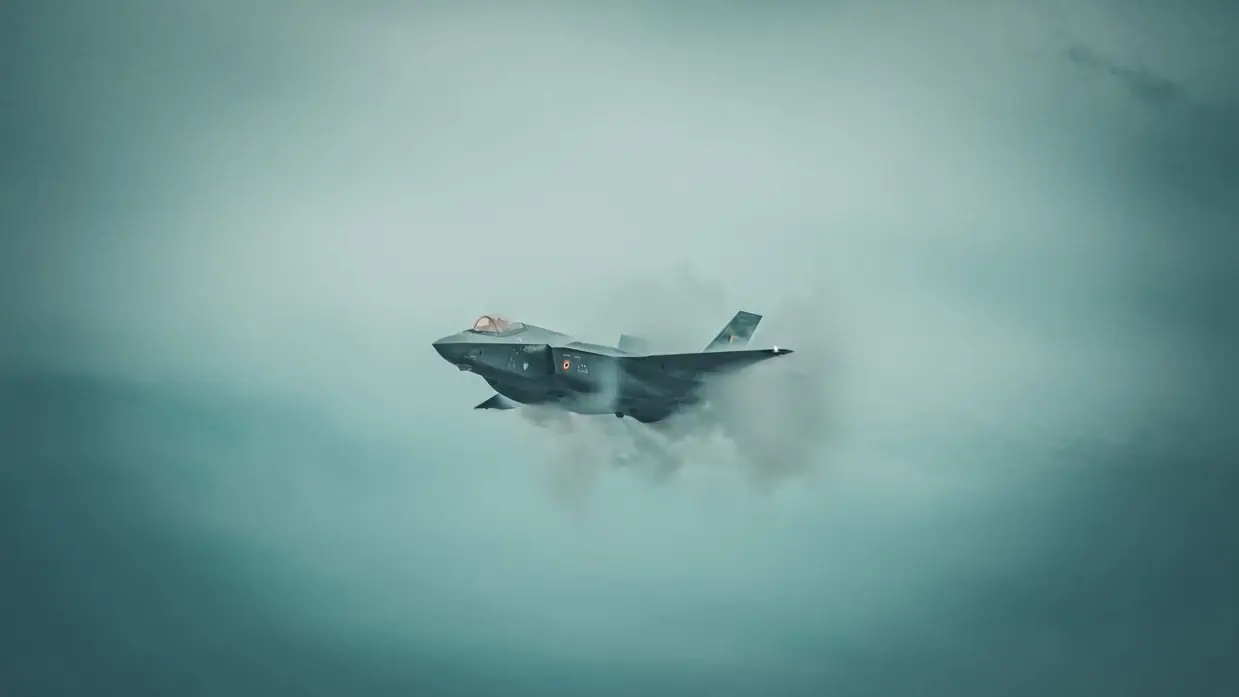 een Belgische F-35 in de lucht met om het toestel een condenswolk. 