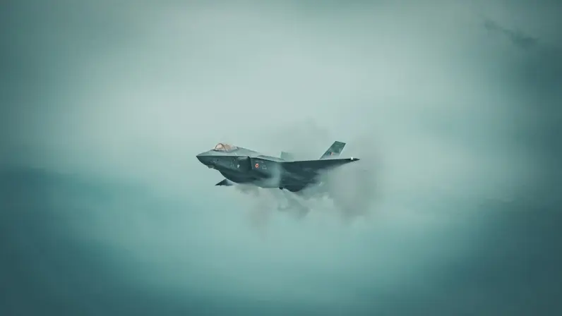een Belgische F-35 in de lucht met om het toestel een condenswolk. 