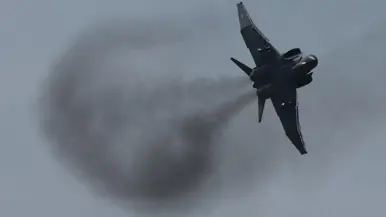  Links en rechts: een vliegtuig trekt een rookspoor en de bocht met blauwe lucht boven.