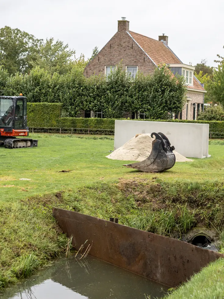 zicht op een sloot, waarin een keerwand is geplaatst.