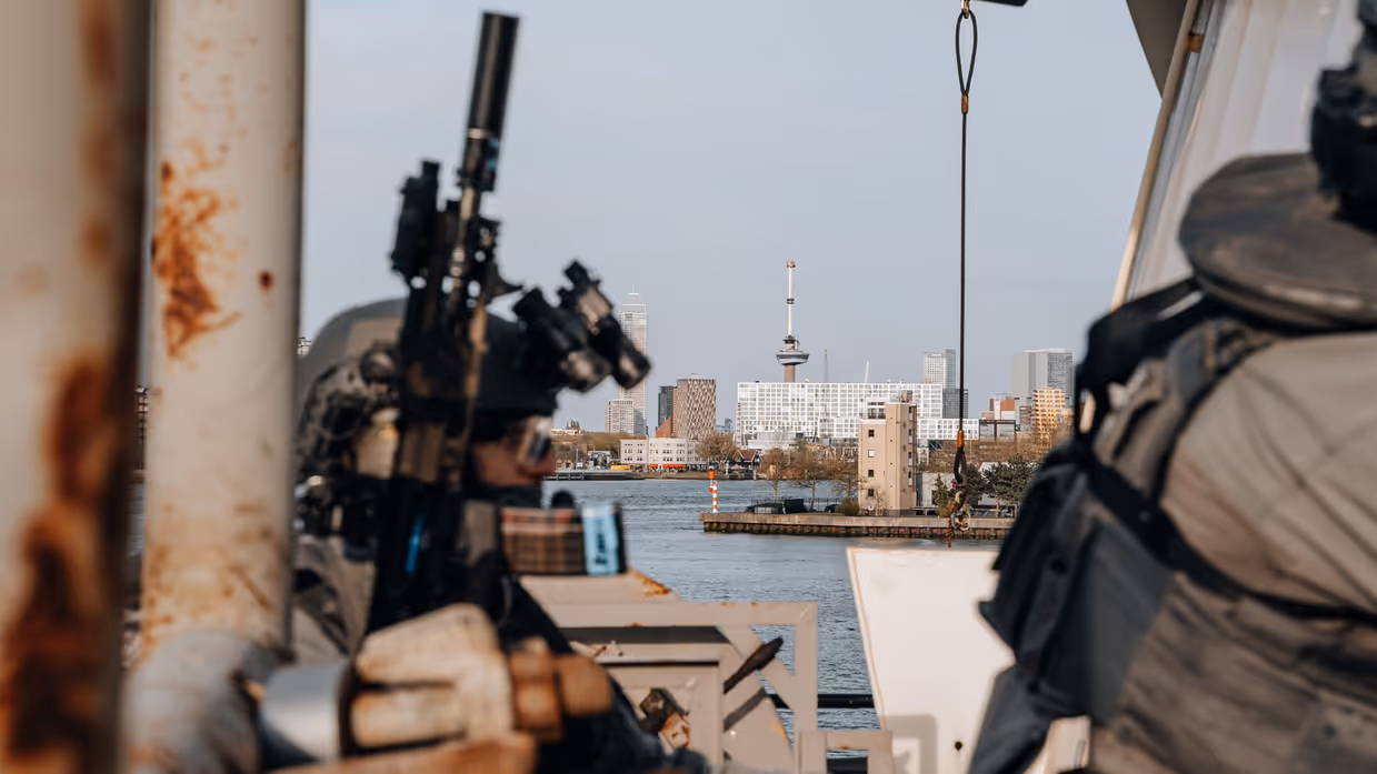 2 militairen oefenen gewapend in een haven.