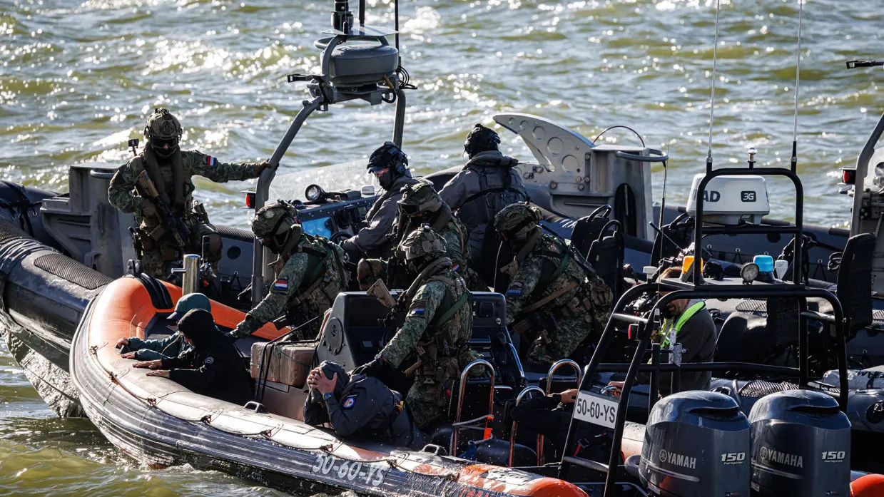  Operators die quasi smokkelaars op een oranje motorboot hebben overmeesterd. 