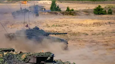 rijdende CV90 pantservoertuigen met stofwolken.&nbsp;