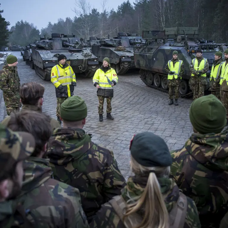 Militairen luisteren in kring naar collega's met gele hesjes.