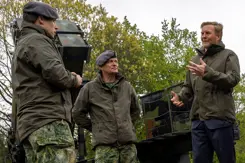 Koning Willem-Alexander in gesprek met 2 militairen. Ze staan voor een Patriot-luchtverdedigingssysteem.