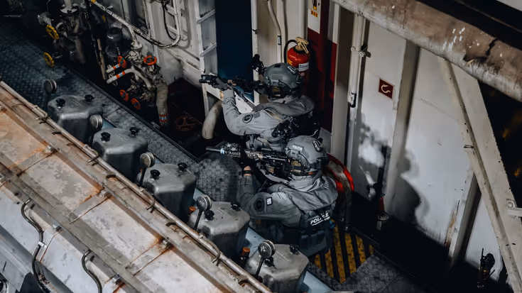 Militairen met getrokken wapen door een gang.