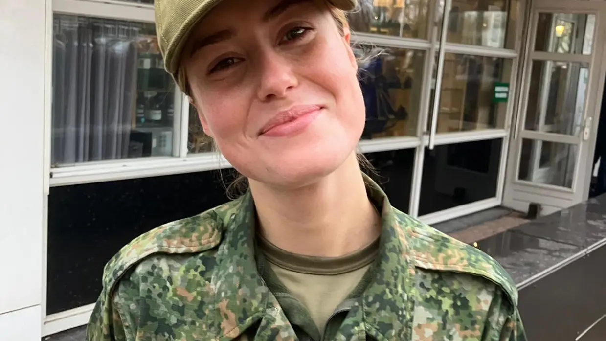 Floor draagt een camouflage-uniform en pet van de Nationale Weerbaarheidstraining.