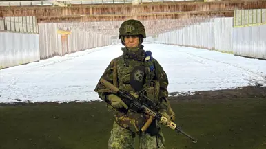 Floor staat in militair tenue met helm en wapen op een schietbaan.