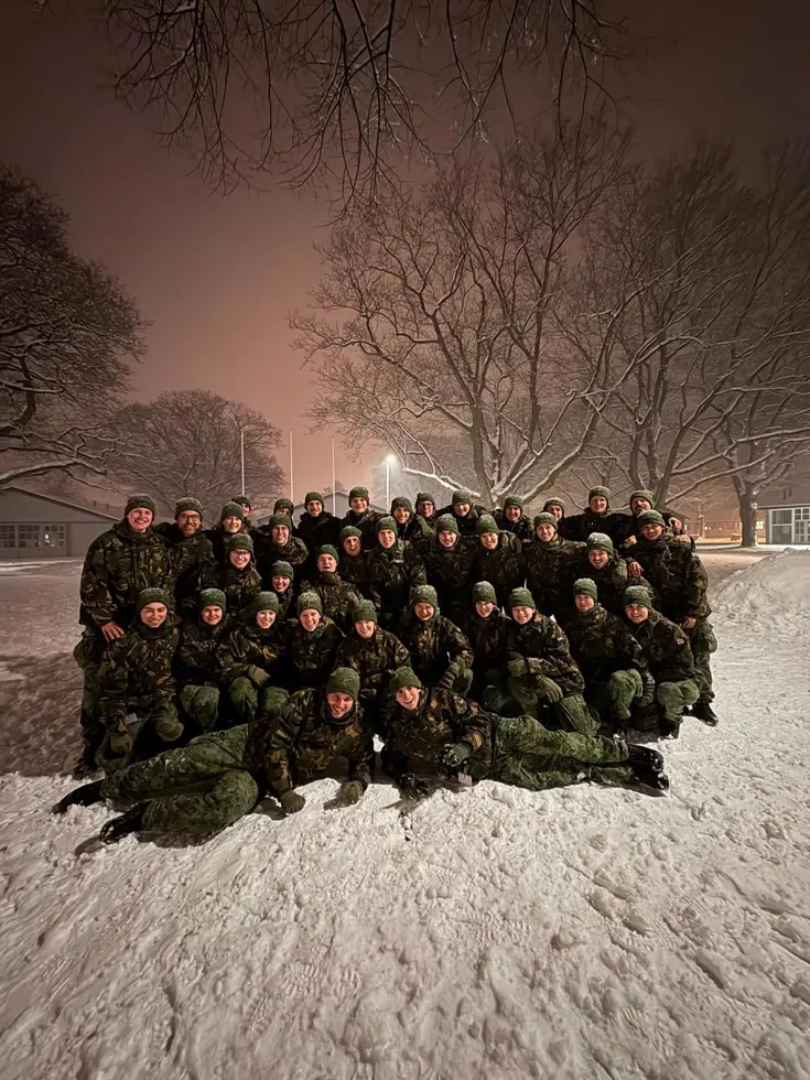  Een groep deelnemers van de Nationale Weerbaarheidstraining poseert samen in de sneeuw tijdens een avondopleiding. 