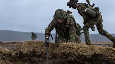 Twee militairen bezig met een metaaldetector.