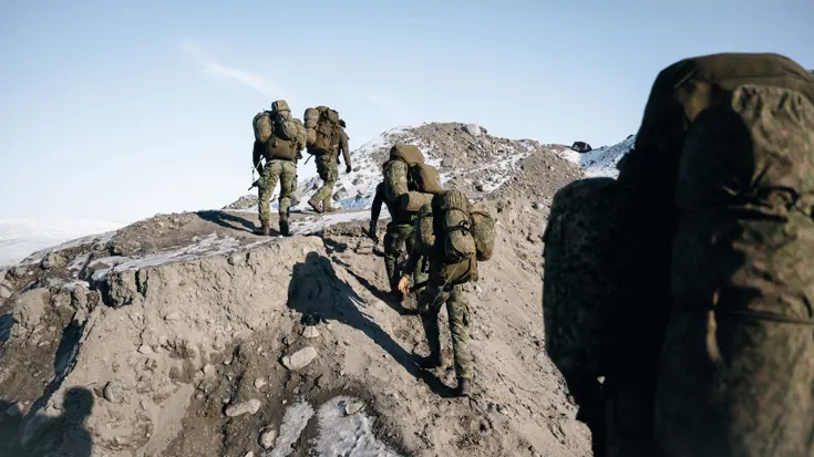 Militairen beklimmen met bepakking een berg.