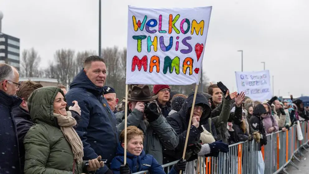 Mensen tonen een spandoek om militairen welkom terug te heten na inzet.