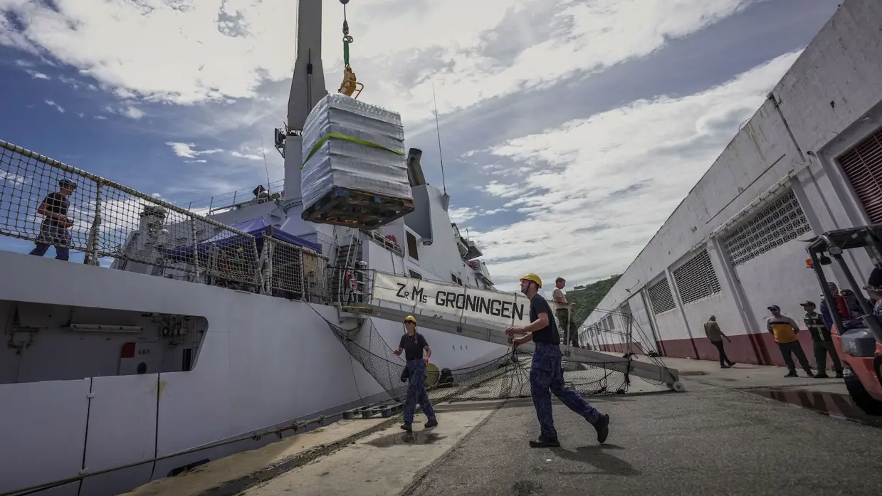 Militairen laten een krat met waterflessen aan dek zetten.